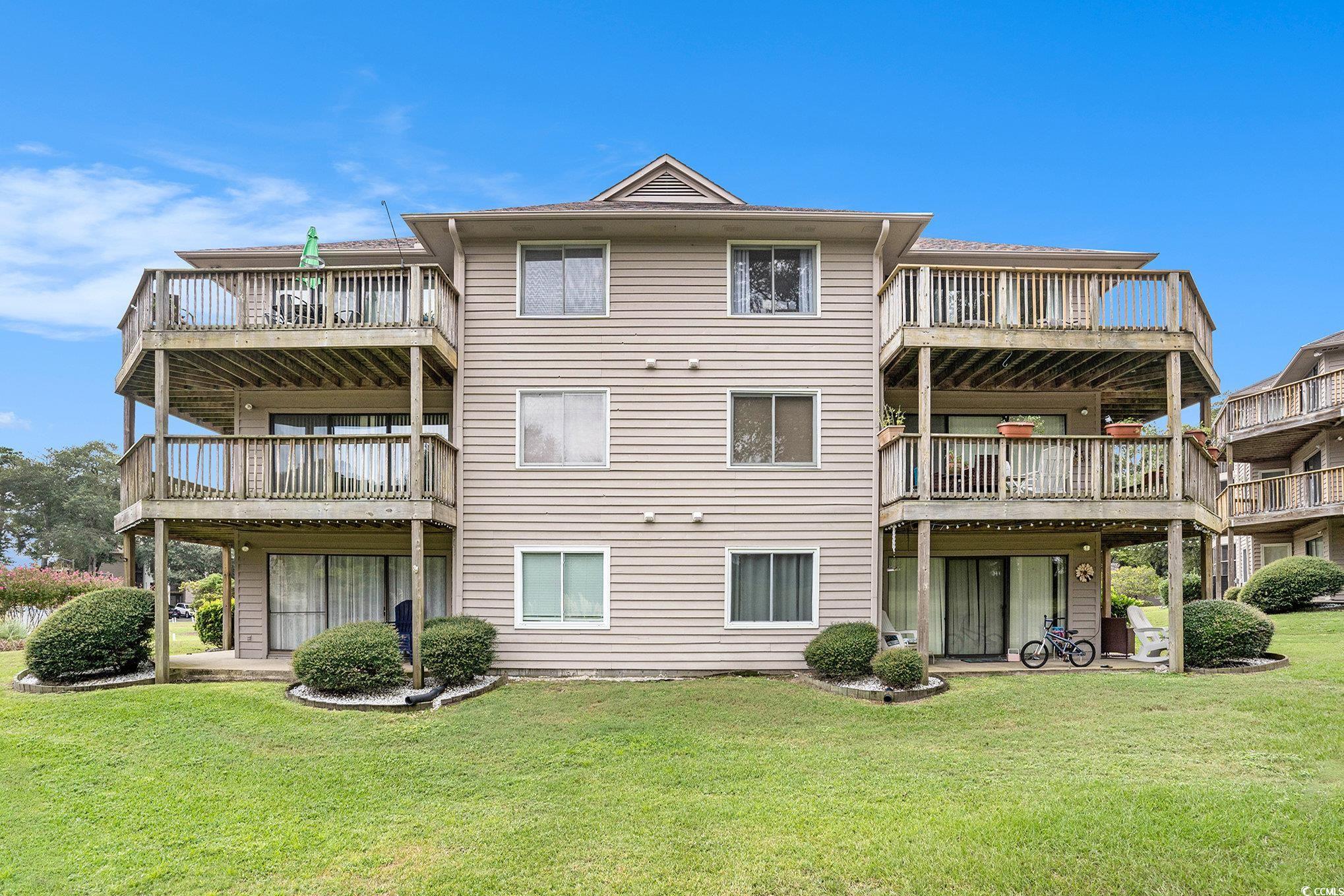 815 Colony Place, Unit 15F Sunset Beach, NC 28468 - Photo 32 of 34 Back of property with a lawn and a balcony