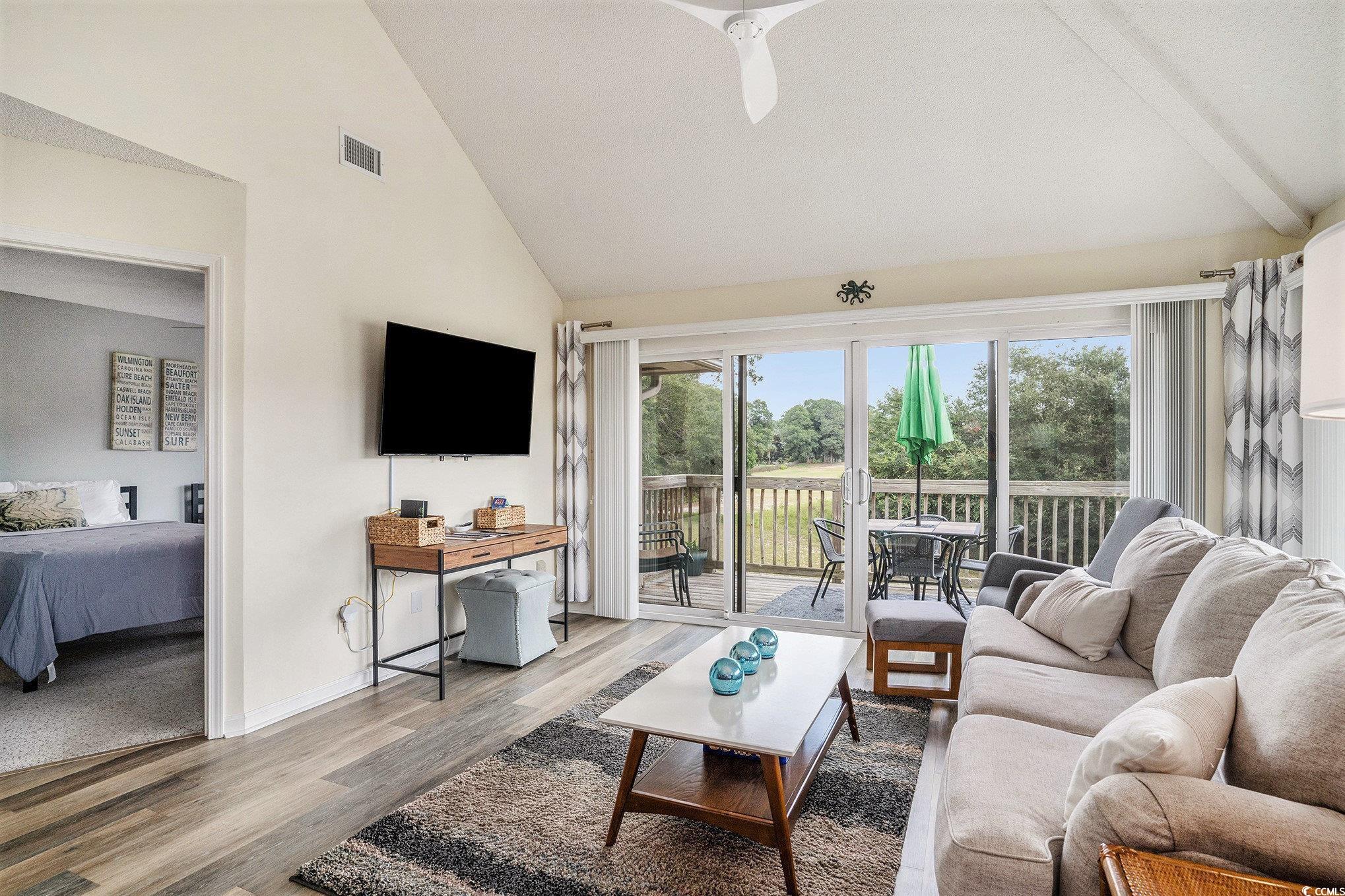 815 Colony Place, Unit 15F Sunset Beach, NC 28468 - Photo 4 of 34 Living area with high vaulted ceiling, wood finished floors, and ceiling fan