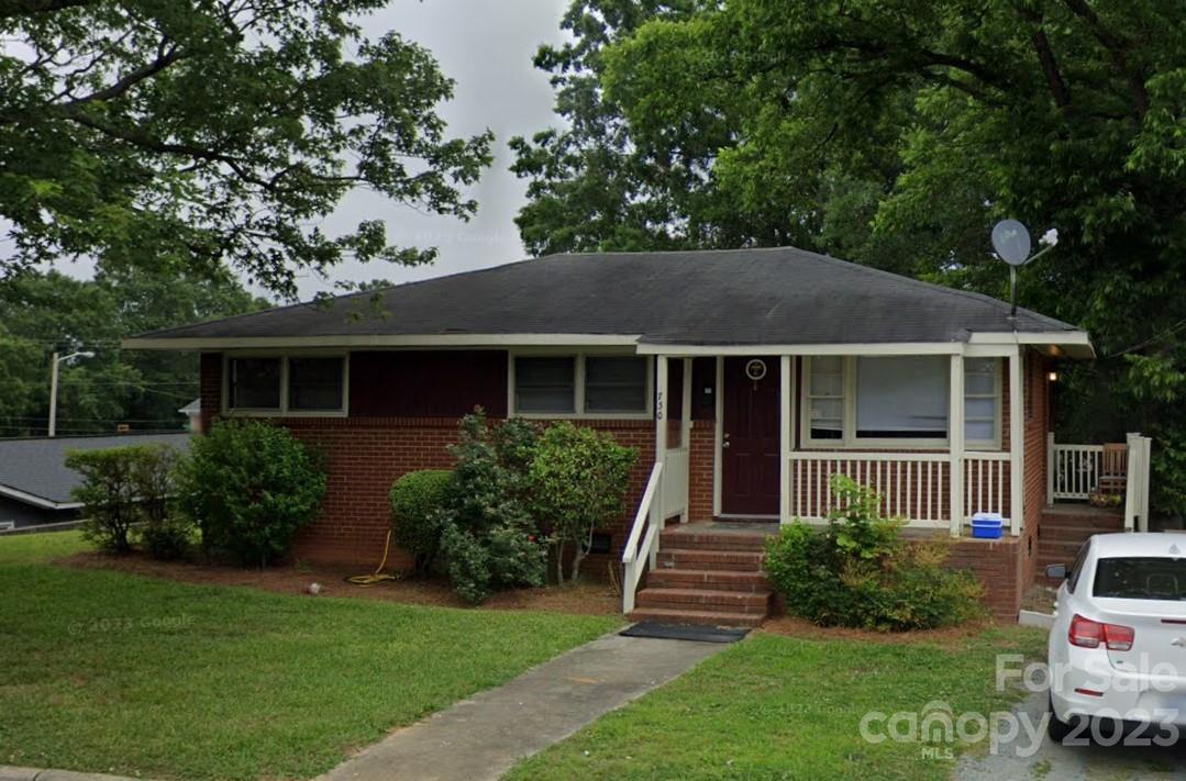 a front view of a house with a yard and potted plants