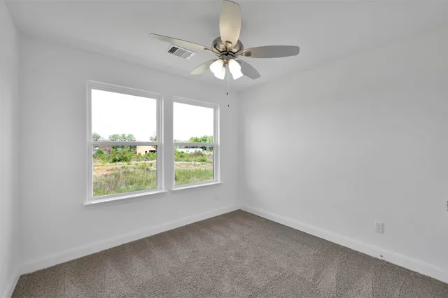 an empty room with a chandelier fan and closet area