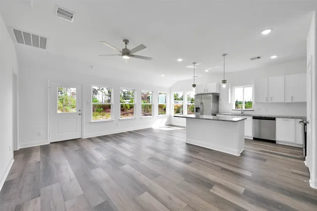 a view of kitchen with kitchen island wooden floors appliances and cabinets