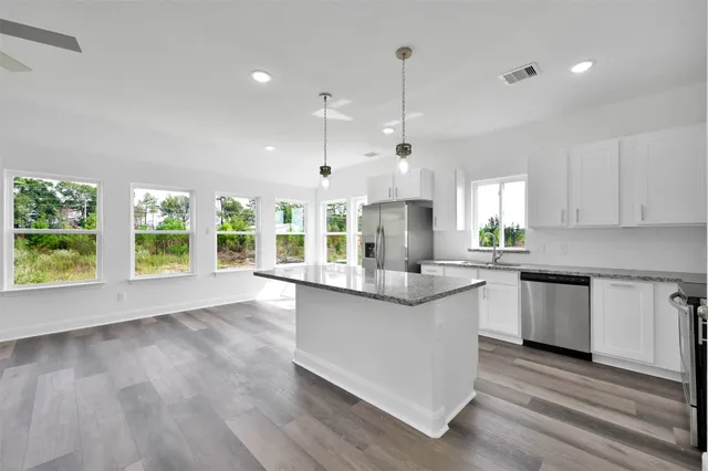 a large kitchen with kitchen island a large counter top space a sink stainless steel appliances and cabinets