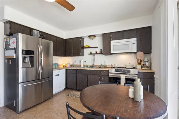 a kitchen with stainless steel appliances granite countertop a stove a refrigerator a sink a dining table and chairs