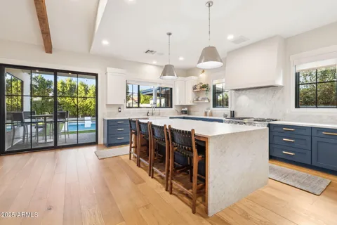 a kitchen with stainless steel appliances granite countertop a stove a sink dishwasher a living room with couches chairs and wooden floor