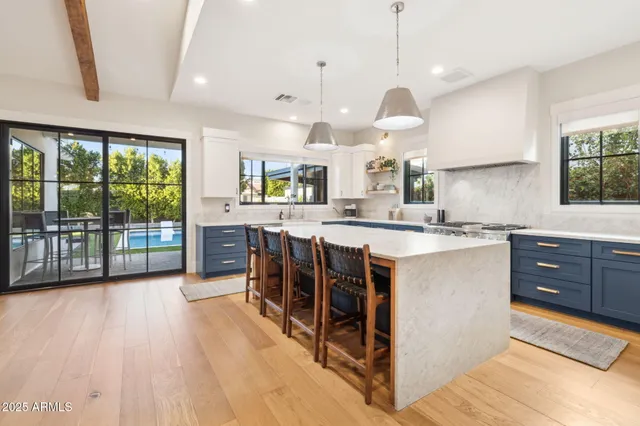 a kitchen with stainless steel appliances granite countertop a stove a sink dishwasher a living room with couches chairs and wooden floor