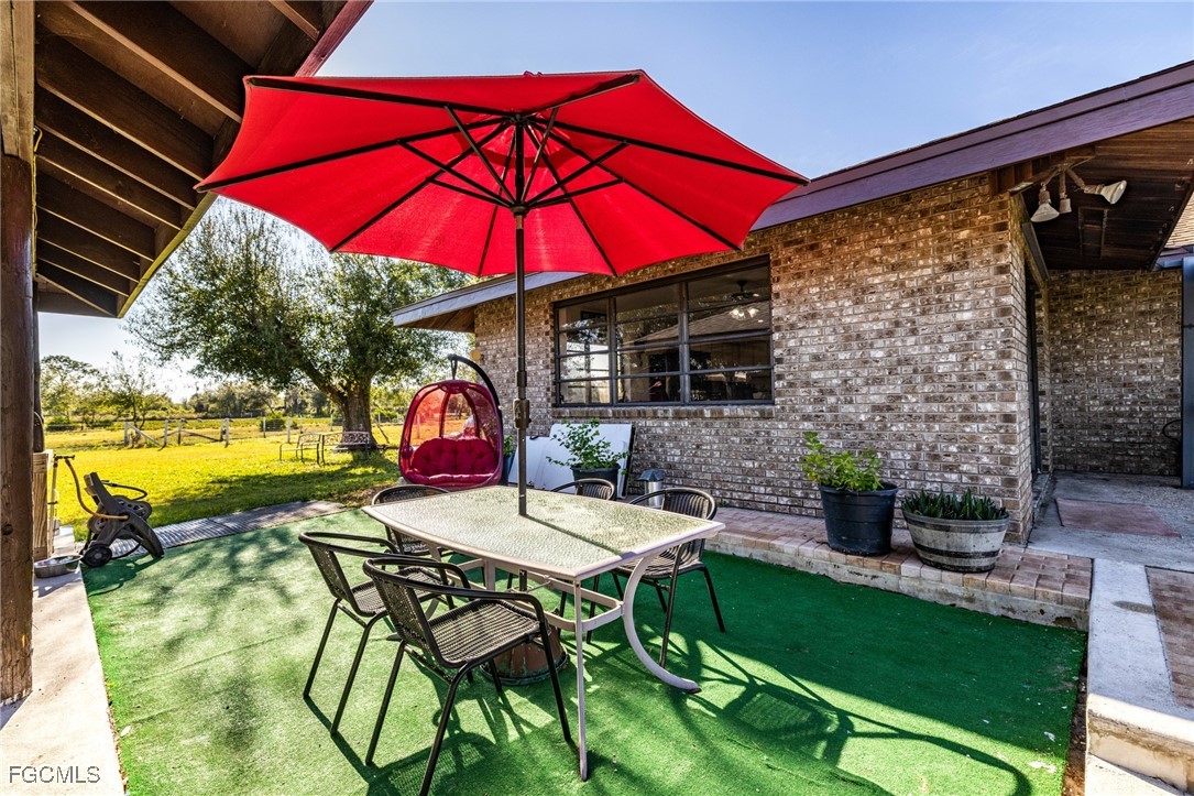 1472 Charolais Road Northwest LaBelle, FL 33935 - Photo 36 of 50 a view of a patio with a table and chairs under an umbrella
