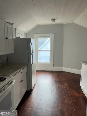 an empty room with wooden floor cabinet and window