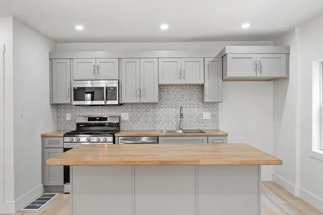 a kitchen with stainless steel appliances kitchen island granite countertop a sink a stove a microwave a counter top and cabinets