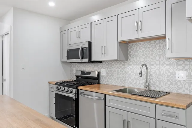 a kitchen with granite countertop white cabinets stainless steel appliances and a sink