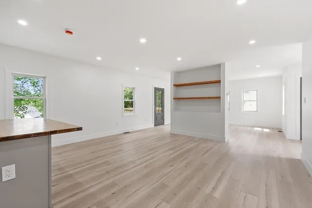 a view of an empty room with a window and wooden floor