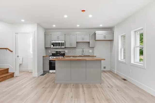 a large kitchen with kitchen island a sink dishwasher a stove and a refrigerator with wooden floor