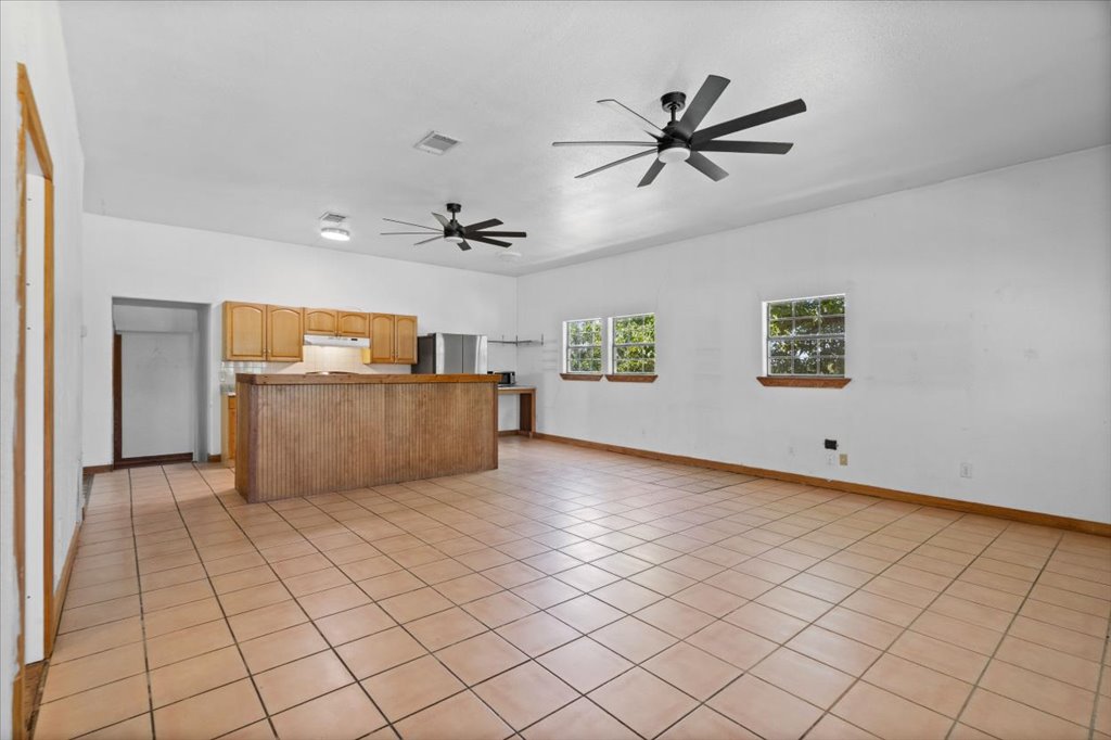 555 Harmon Hills Road, Unit A Dripping Springs, TX 78620 - Photo 13 of 29 A spacious, open-plan area featuring a kitchen island and durable tile flooring throughout.