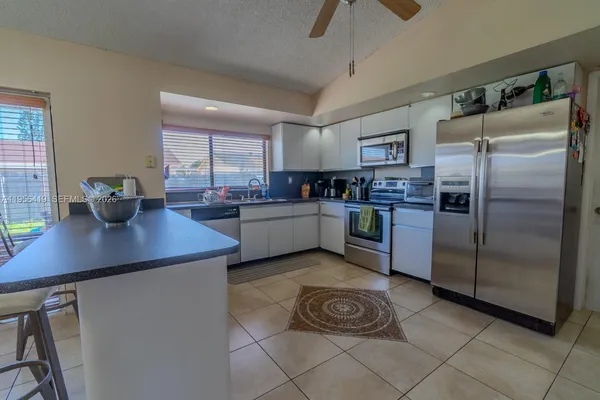 a kitchen with stainless steel appliances granite countertop a sink a stove a refrigerator cabinets and dining table