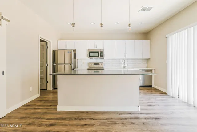 a kitchen with stainless steel appliances granite countertop a refrigerator sink and white cabinets