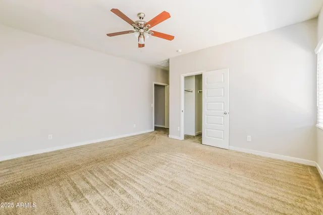 an empty room with a ceiling fan and wooden floor
