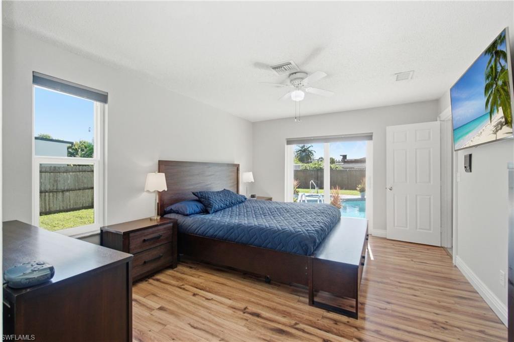 3022 47th Street Southwest Naples, FL 34116 - Photo 24 of 46 Spacious master bedroom featuring wood-finish flooring, a ceiling fan, and direct access to a private backyard with a swimming pool