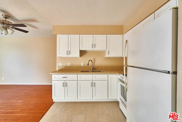 a kitchen with a sink a refrigerator and cabinets