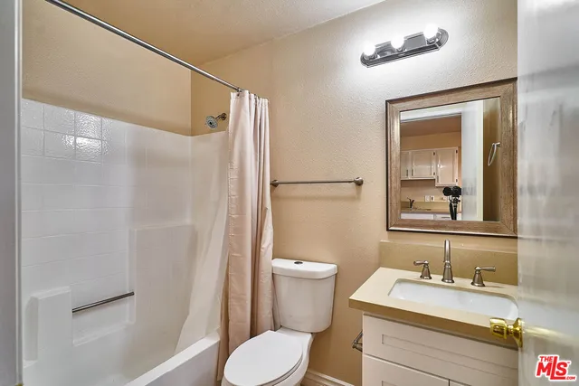 a bathroom with a granite countertop sink toilet a mirror and shower