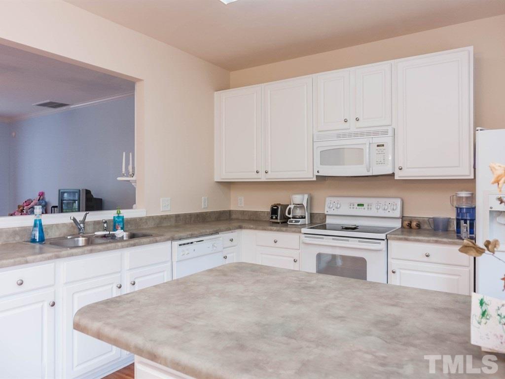 8149 Rhiannon Road Raleigh, NC 27613 - Photo 12 of 25 a kitchen with stainless steel appliances granite countertop a stove a sink and white cabinets