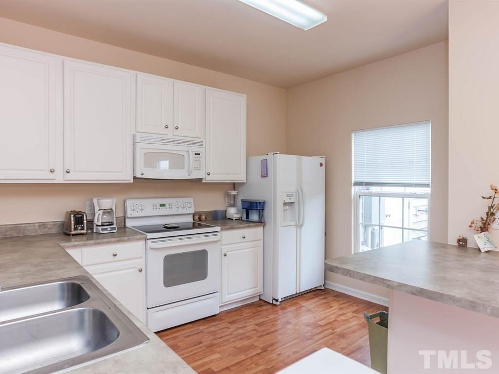 8149 Rhiannon Road Raleigh, NC 27613 - Photo 10 of 25 a kitchen with white cabinets and white appliances