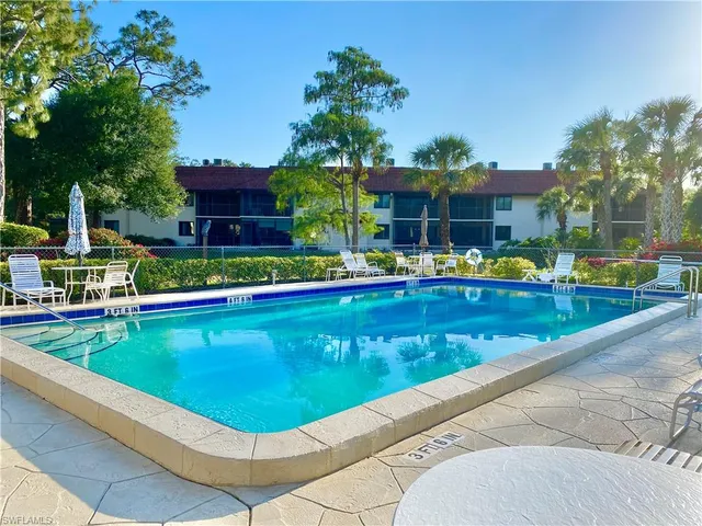 a view of a swimming pool with a table and chairs under an umbrella