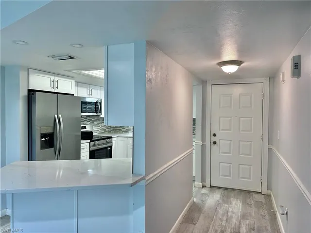 a view of a kitchen with a sink and dishwasher a refrigerator with wooden floor