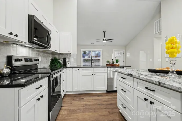 a kitchen with stainless steel appliances granite countertop a sink and a stove