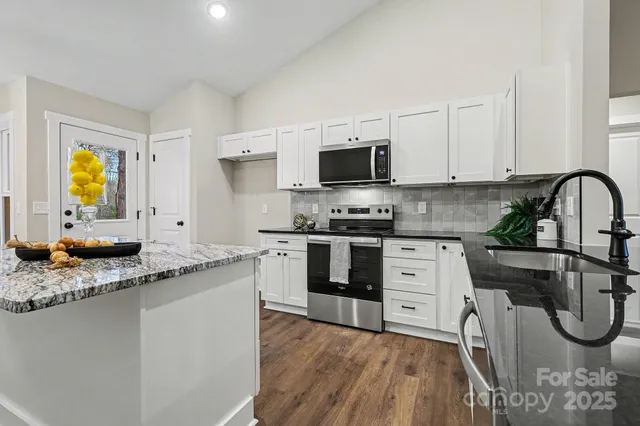 a kitchen with stainless steel appliances granite countertop a stove a sink and a microwave