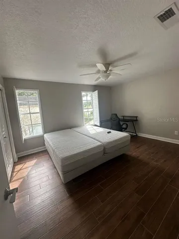 an empty room with wooden floor and windows