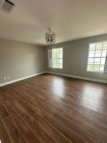 a view of an empty room with wooden floor and a chandelier