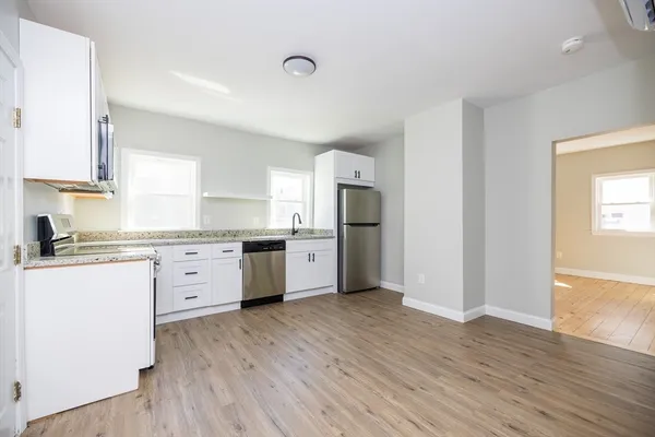 a kitchen with granite countertop a refrigerator cabinets and wooden floor