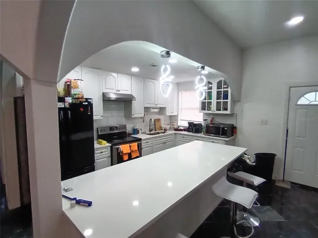 a large kitchen with stainless steel appliances a large counter top a refrigerator a stove a sink and a stove