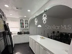 a kitchen with stainless steel appliances kitchen island granite countertop a refrigerator a sink dishwasher a stove and white cabinets with wooden floor