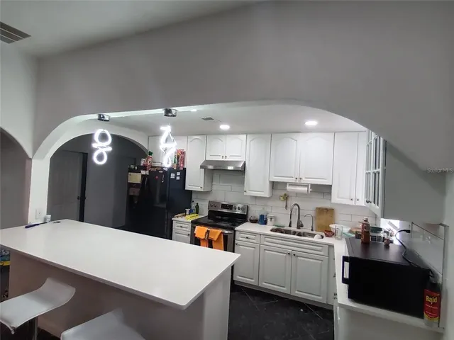 a large kitchen with kitchen island a sink stainless steel appliances and cabinets