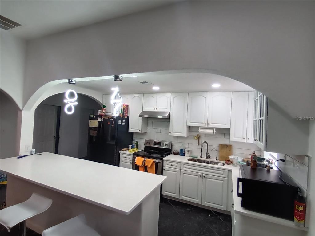 7040 Lumberton Road Zephyrhills, FL 33540 - Photo 3 of 34 a large kitchen with kitchen island a sink stainless steel appliances and cabinets