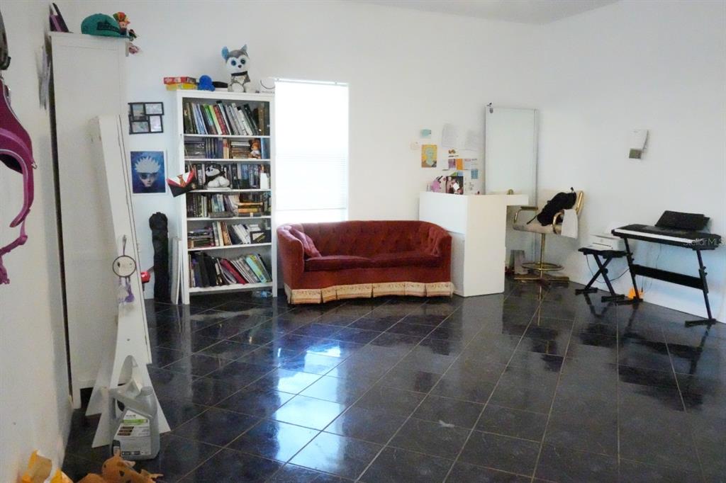 7040 Lumberton Road Zephyrhills, FL 33540 - Photo 5 of 34 a living room with furniture a rug and a book shelf