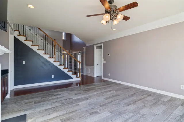 a view of an empty room with wooden floor fireplace and a window