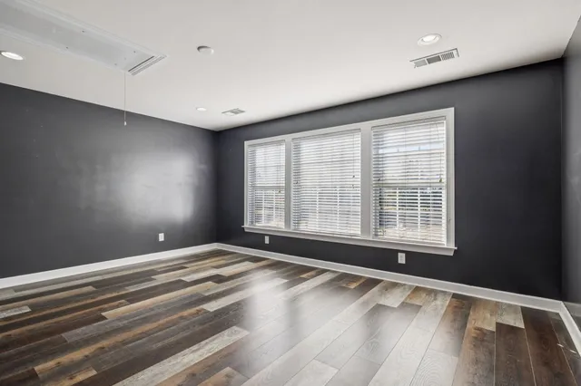 an empty room with wooden floor closet and windows