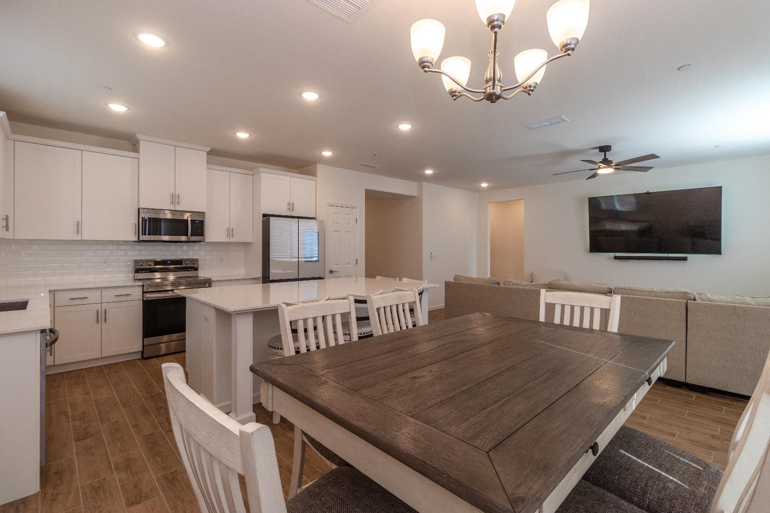 1158 Encore Way West Madera, CA 93636 - Photo 15 of 45 a kitchen with stainless steel appliances granite countertop a stove top oven a sink dishwasher a dining table and chairs with wooden floor
