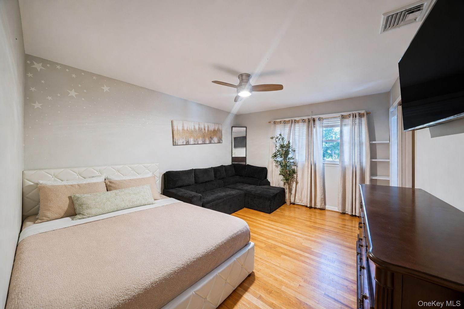 31 Crooked Hill Road Huntington, NY 11743 - Photo 19 of 32 Bedroom featuring wood-finish flooring, a ceiling fan with integrated lighting, window with light-filtering drapes, and built-in shelving
