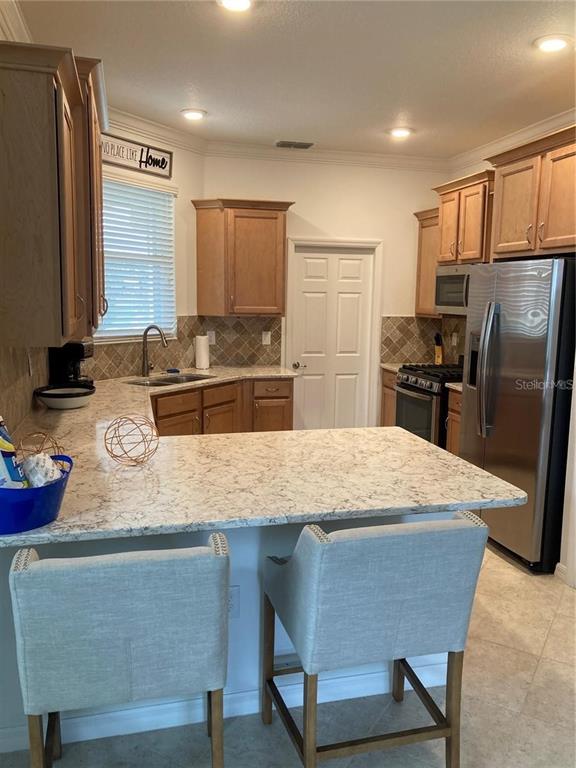 9877 Southwest 99th Loop Ocala, FL 34481 - Photo 2 of 10 a kitchen with stainless steel appliances granite countertop wooden cabinets a refrigerator and a sink