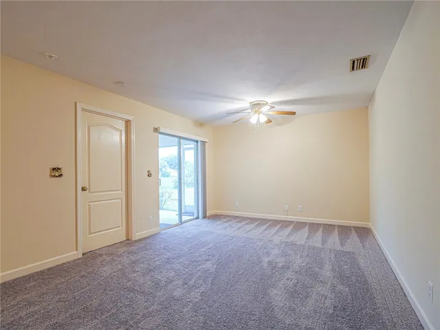 an empty room with a chandelier fan and windows