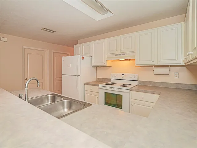 a kitchen with a sink dishwasher stove and white cabinets