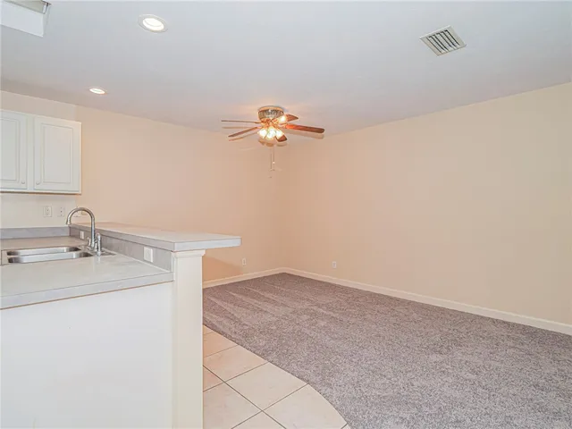 an empty room with a chandelier fan and windows