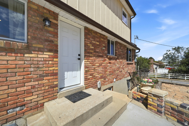 Brick exterior with a white entry door, exterior light fixture, and concrete steps