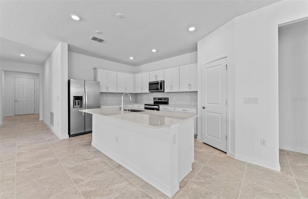 4147 Feldspar Lane Spring Hill, FL 34609 - Photo 3 of 22 a kitchen with stainless steel appliances a refrigerator sink stove and white cabinets