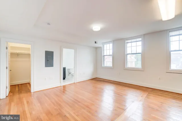 an empty room with wooden floor and windows