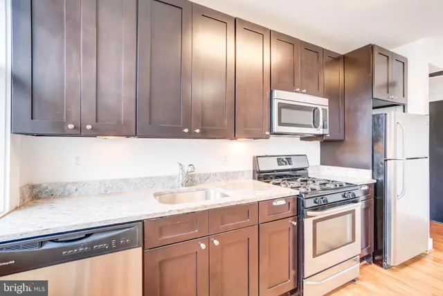 a kitchen with granite countertop stainless steel appliances a stove cabinets and a counter top space