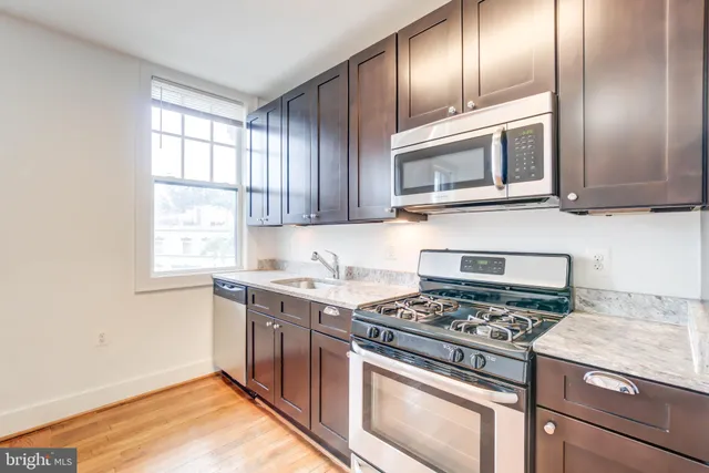 a kitchen with granite countertop cabinets stainless steel appliances and a window
