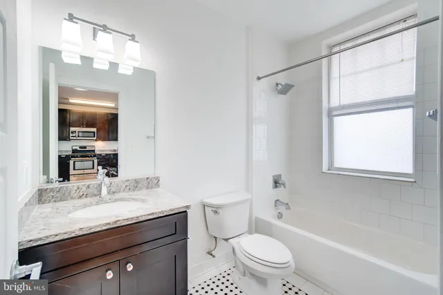 a bathroom with a granite countertop sink a toilet a mirror and shower